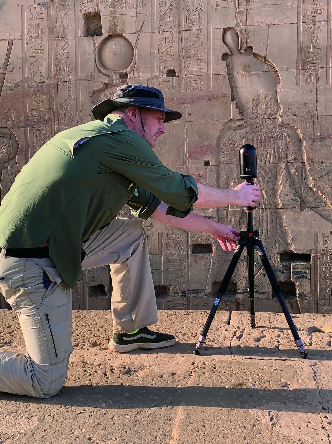 un hombre usando una cámara sobre un trípode tomando fotografías de graffitis antiguos